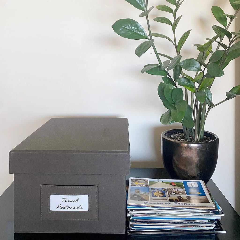 A stack of postcards and a postcard storage box